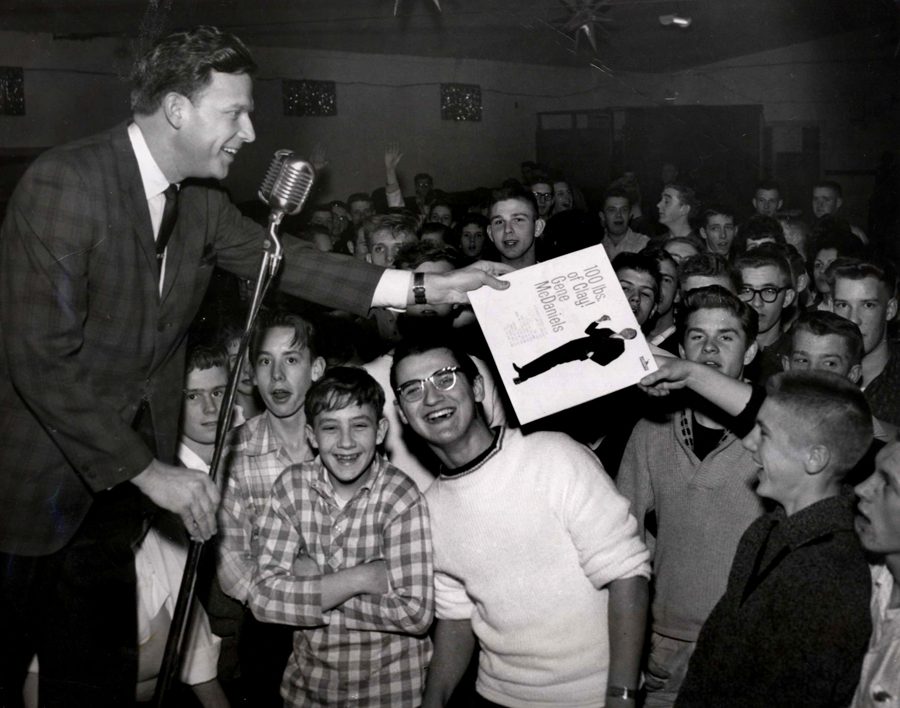 A man is on stage with a microphone and crowd.