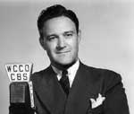 A man in suit and tie holding onto a microphone.