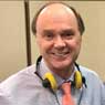 A man with headphones on smiling for the camera.