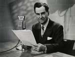 A man sitting at a desk in front of a microphone.