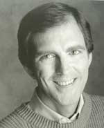 A man with short hair and wearing a sweater.
