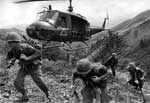 A helicopter is flying over the ground with soldiers.